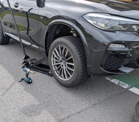 Floor jack under the BMW X5 with the front wheel raised