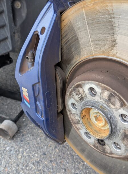 Blue M Sport front brake caliper with the wheel removed