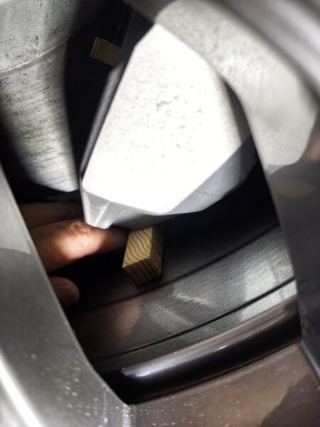 Wooden gauge pushed into the caliper-to-wheel gap