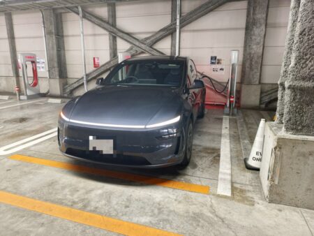 A Tesla Model YL charging at a Supercharger inside a multi-storey car park