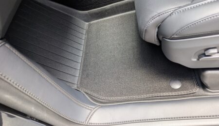 A carpet mat layered over the TPE tray on the passenger side