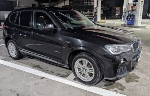 夜のガソリンスタンドで最後の洗車をするBMW F25 X3