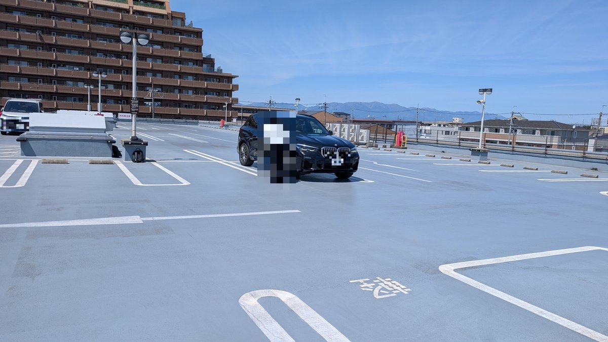 屋上駐車場でBMW X5の査定と撮影をする担当者
