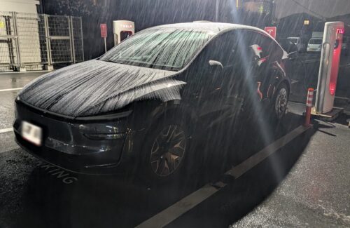 雨の夜、スーパーチャージャーで充電するテスラ モデルYL