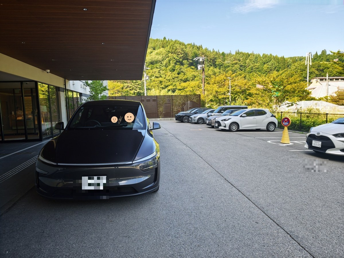 ホテル前の駐車場に停めたモデルYL。奥は緑の山が広がっている