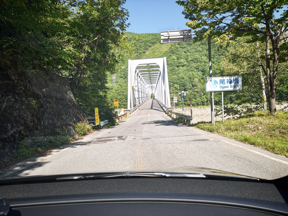 尾神橋の手前。緑に囲まれた道路と橋の入口