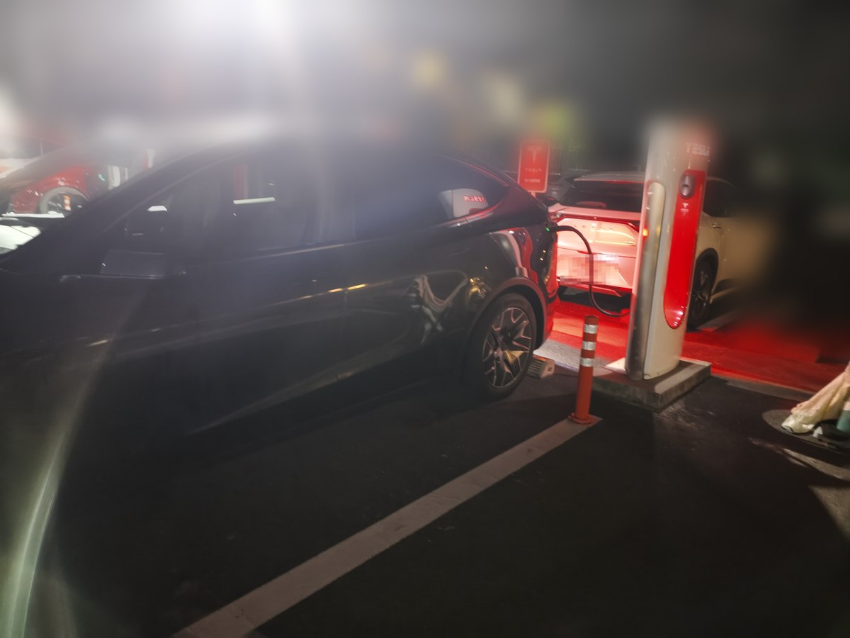 夜のスーパーチャージャーで充電中のモデルYL。隣のストールにも別の車が入っている