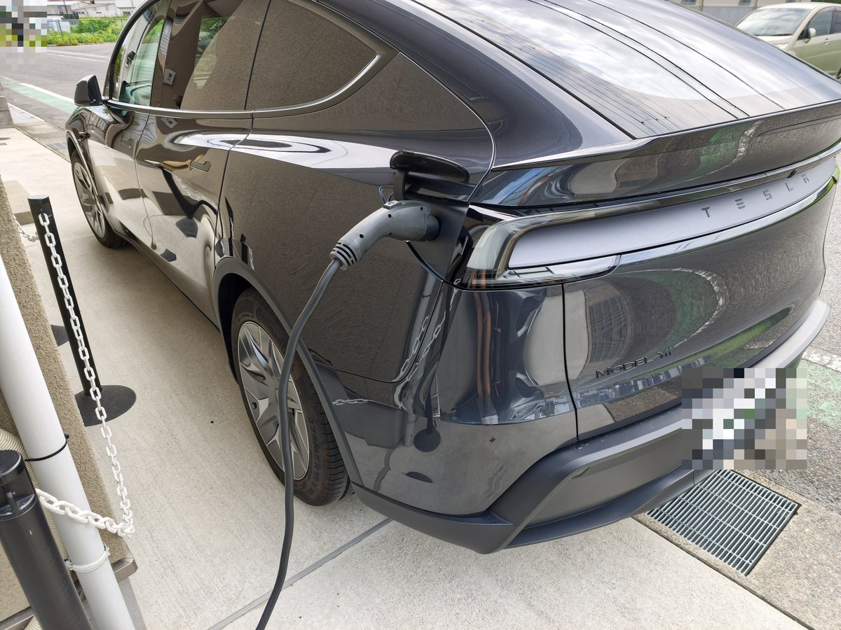 出発前、自宅の駐車スペースで充電ケーブルをつないだテスラ Model YLの後ろ姿