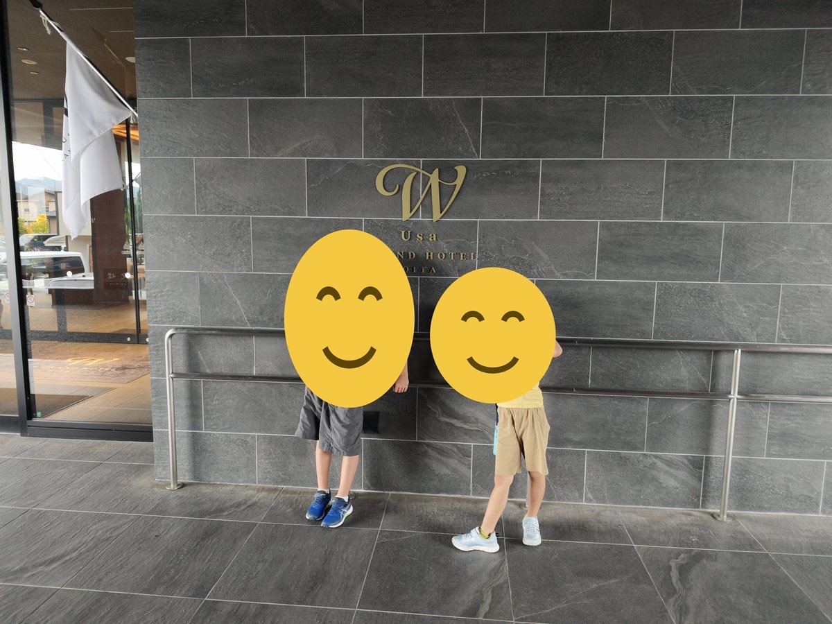 宇佐グランドホテルの壁の前に立つ子ども2人