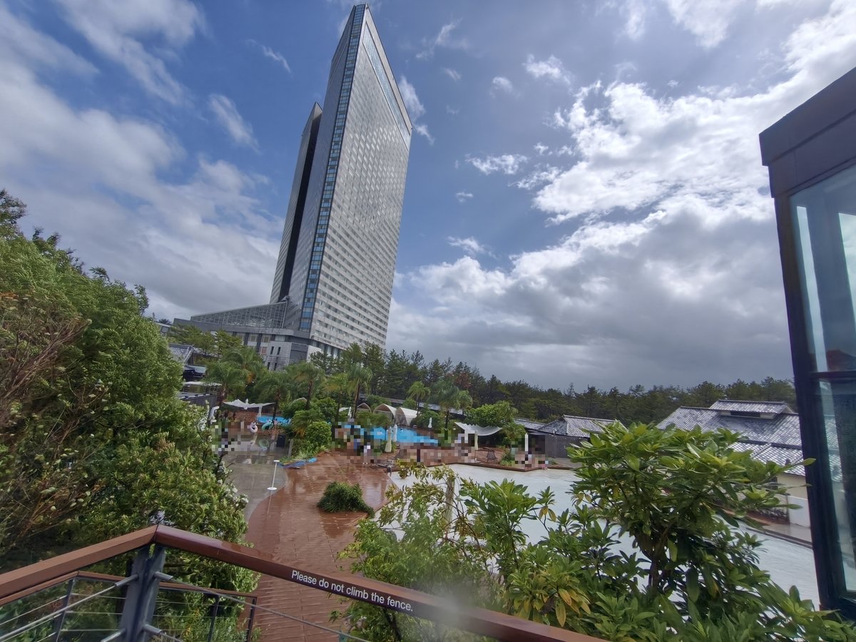 フェンス越しに見上げたホテル棟と屋外の水遊びエリア
