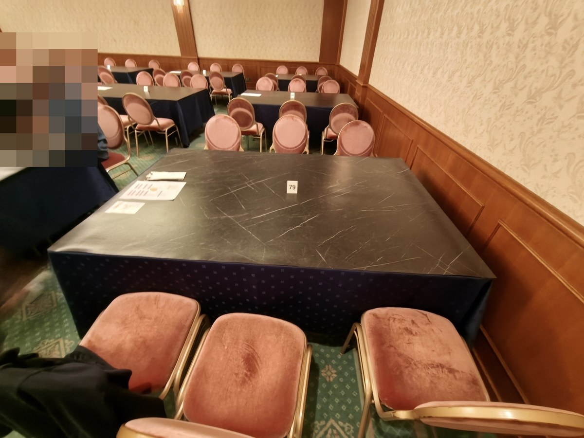 黒いクロスをかけた長テーブルと宴会用の椅子、卓番のカード