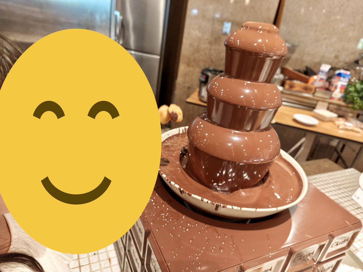チョコレートファウンテンにマシュマロを浸す子ども