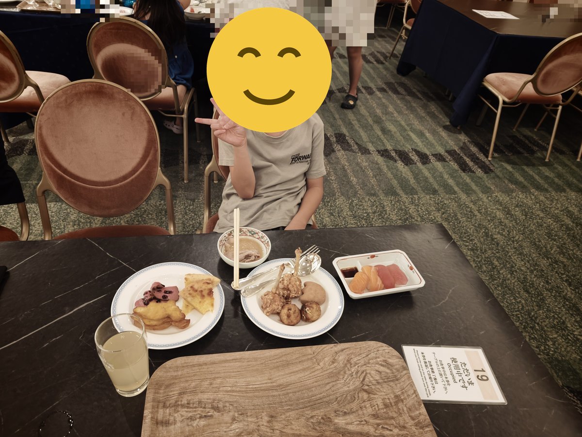 テーブルで料理を前にピースサインをする子ども