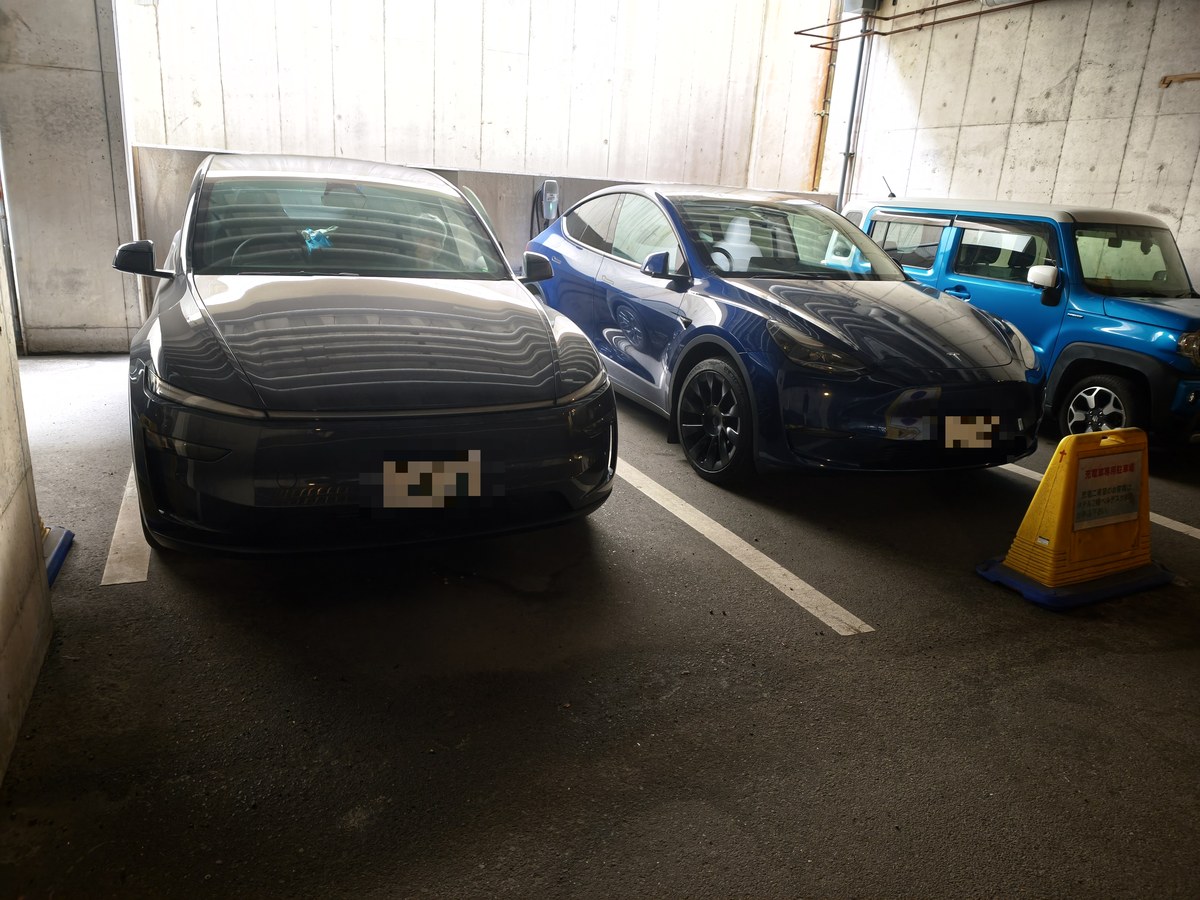 ホテルの屋内駐車場に並んで停まる2台のテスラと軽SUV。ナンバープレートにはモザイクをかけている