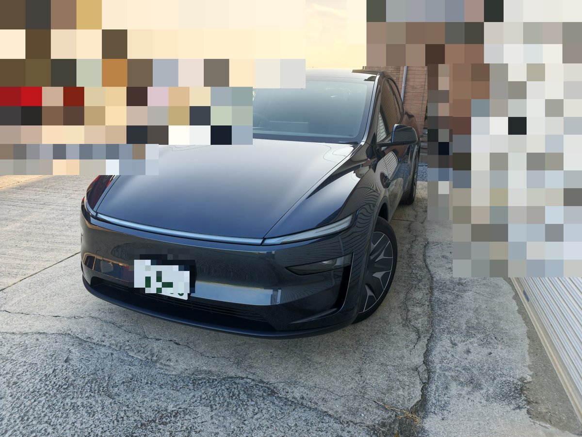 飛び石修理の工房に到着したテスラ Model YLの正面。背景はモザイク処理